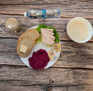 Zdjęcie przedstawia Dietę podstawową:  Kasza manna z jabłkiem prażonym Chleb mieszany pszenno-żytni Masło extra Kawa zbożowa z mlekiem Miód Pasta z pieczonych buraków dieta Woda mineralna Szynkowa dębowa drobiowa kiełbasa grubo rozdrobniona Sałata zielona